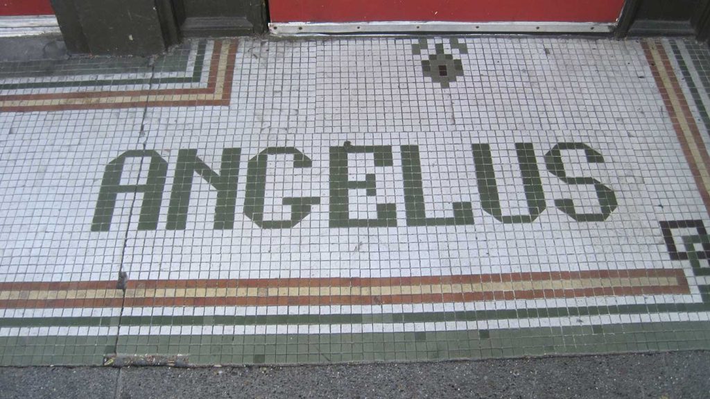 Green tile letters say Angelus, white background, green, red, yellow striped border