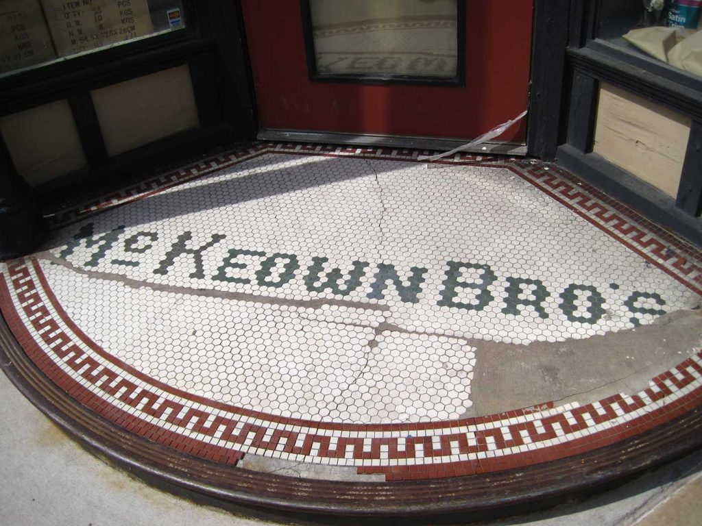 McKeown Bros letters in tile, white background, curved front on corner entry, red zigzag border