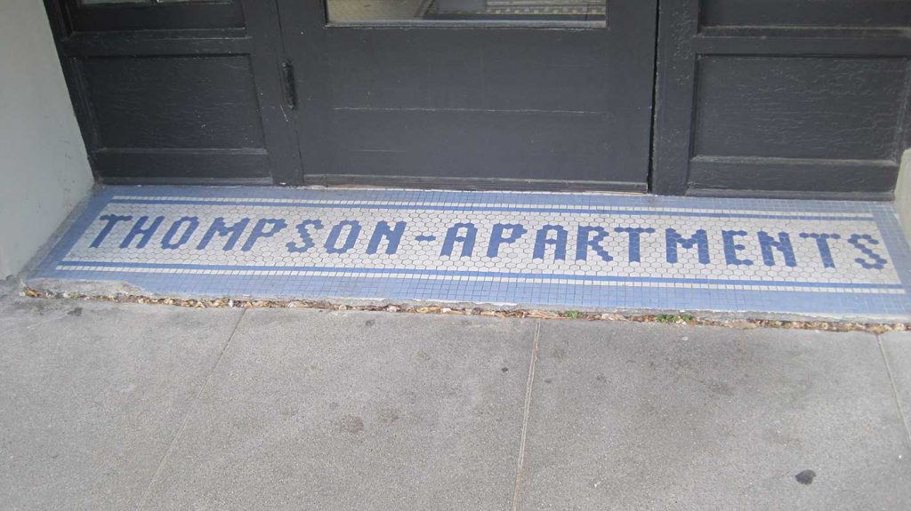 Thompson Apartments in blue letters, white background, blue border