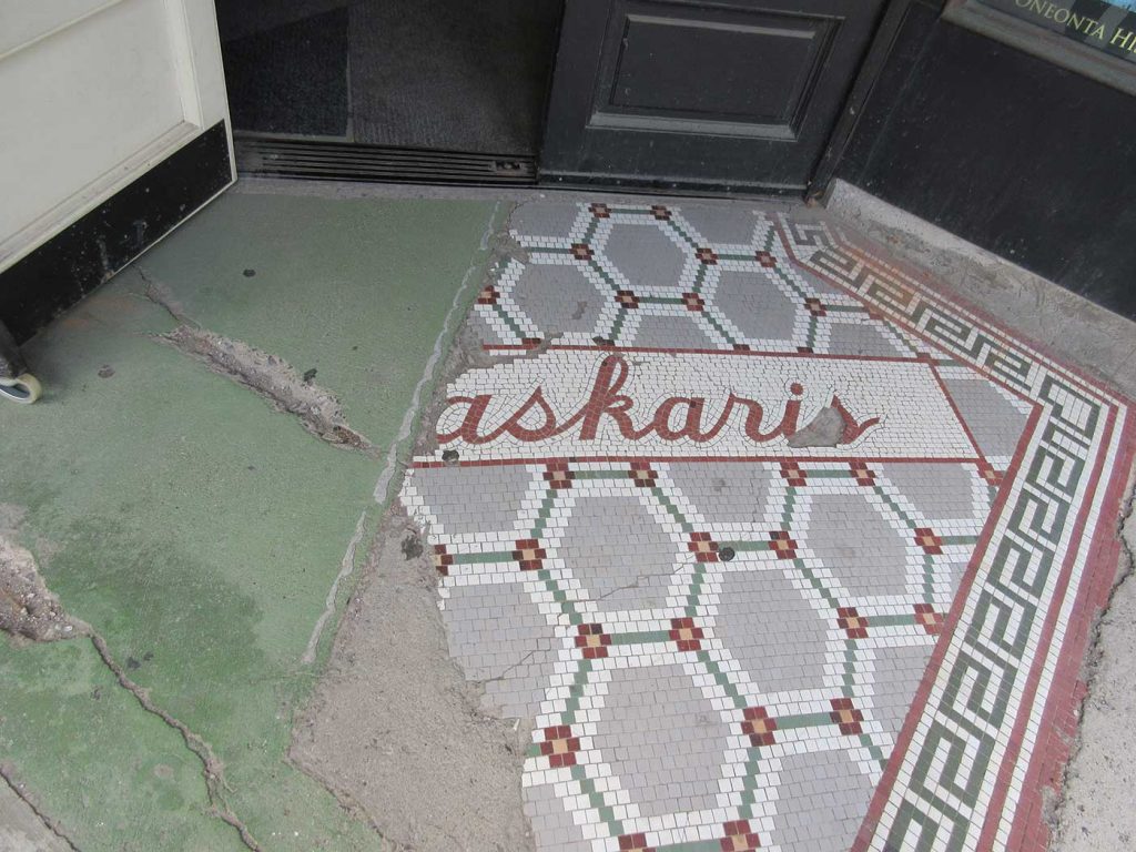 Remnant of gray, red and white octagonal pattern and the letters askaris in script in red on white background
