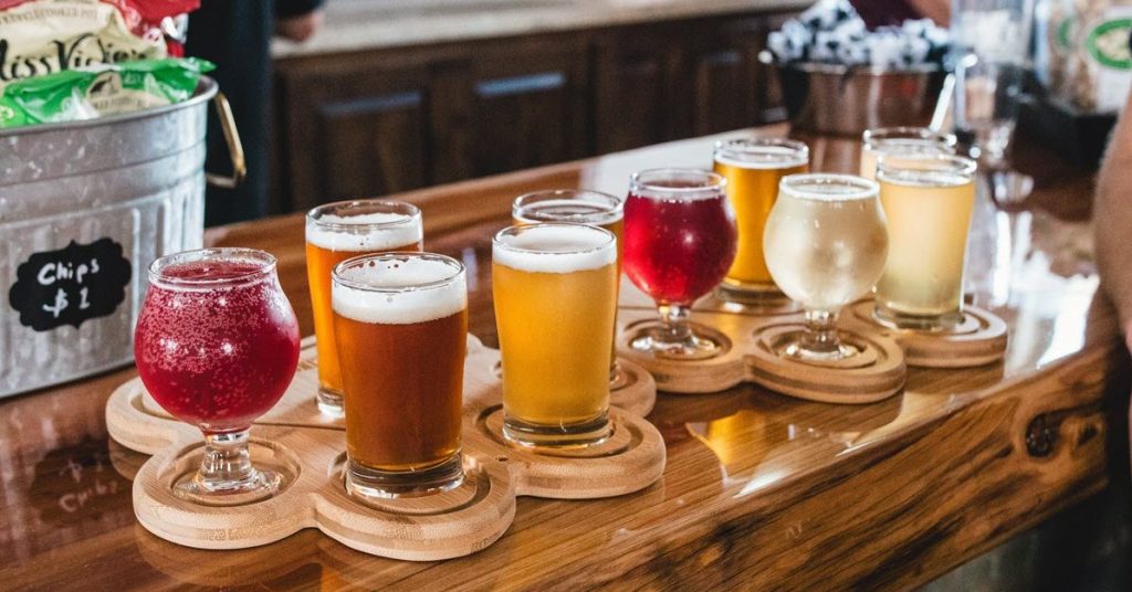 A collection of filled beer glasses on a wooden bar.