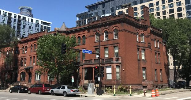 Older 3 story brick building with newer apartments behind