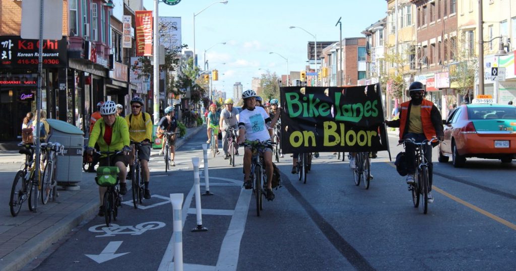 Cyclists with Bike Lane on Bloor sign