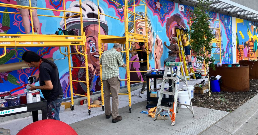 Artists work on painting Faces of Minneapolis by Hend Al-Mansour