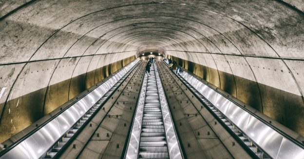 Looking upward at a long set of three escalators in an underground metro station.