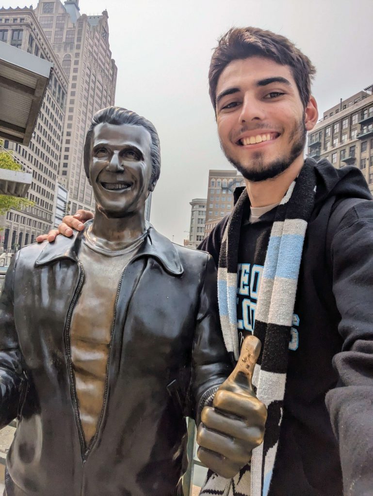 A man stands next to a statue of the Fonz from the TV series "Happy Days."