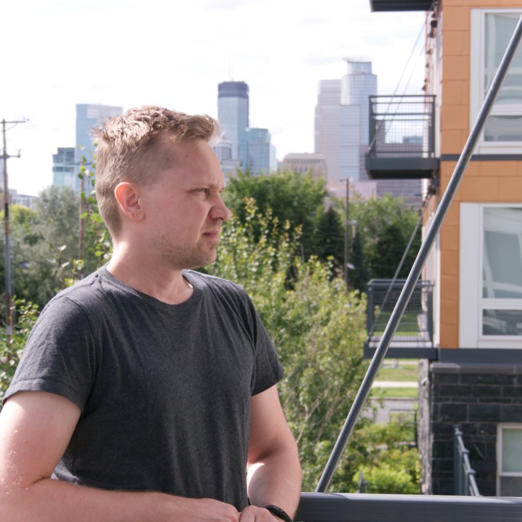A man on an apartment balcony gazes at the view.