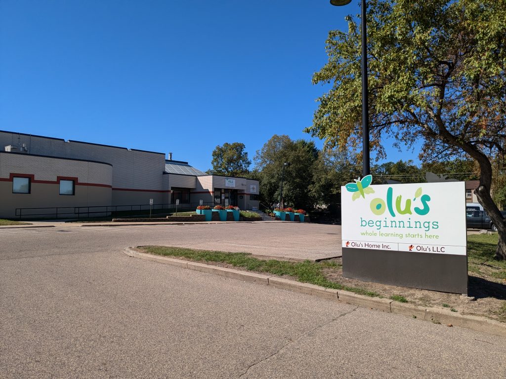 Olu's Beginnings, a children's learning center, has a colorful sign with lime green and aqua letters and a butterfly.