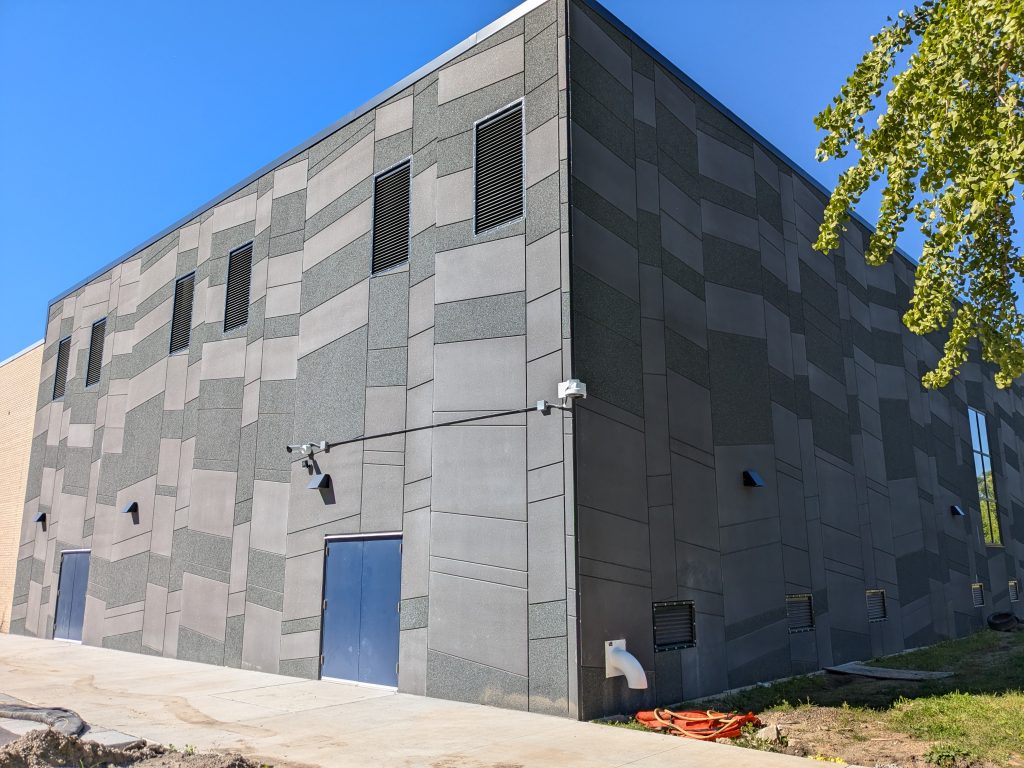 North High School is under construction. This photo shows the blue doors and array of gray tiles that adorn a finished portion of the building.