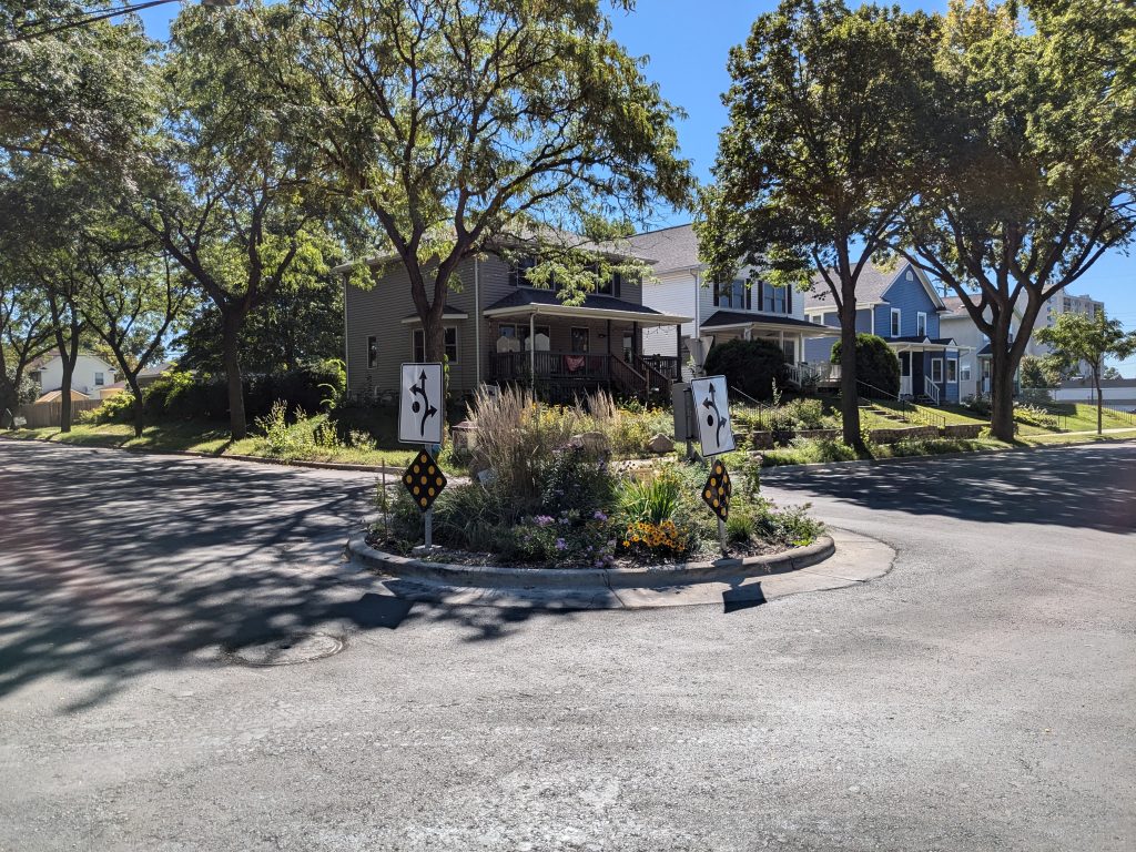 A roundabout, or traffic-calming circle, has plantings inside it.