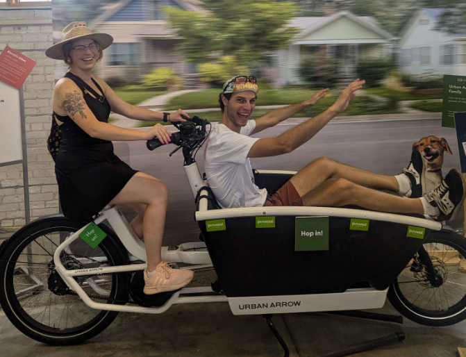 Streets.mn contributors Stina Neel and Ian R Buck on a cargo bike at the Minnesota State Fair e-bike exhibit.