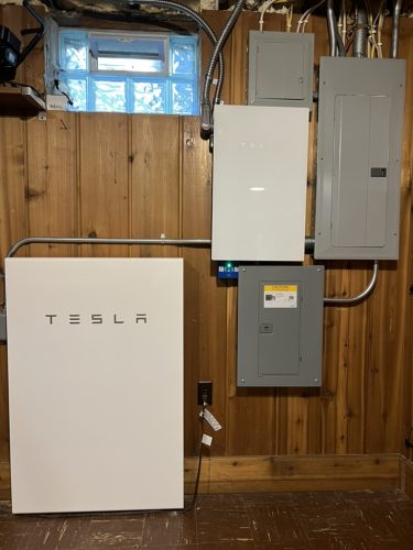 Tesla battery (with logo) in my basement. The other white box and gray box near it connect it to the main panel. The 300-pound battery will work even if the basement floods up to the logo.