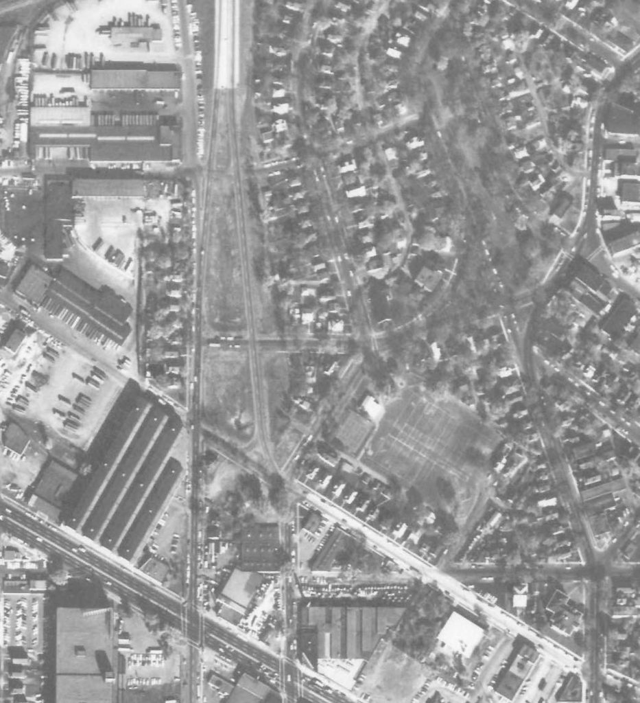 A black-and-white aerial photograph of South St. Anthony Park from 1964, showing a mix of industrial and residential areas. Industrial buildings dominate the left side, while curved residential streets are on the right.