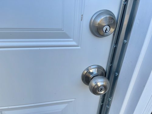 A garage service door with a deadbolt lock and anti-pry enhancements to discourage break-ins.