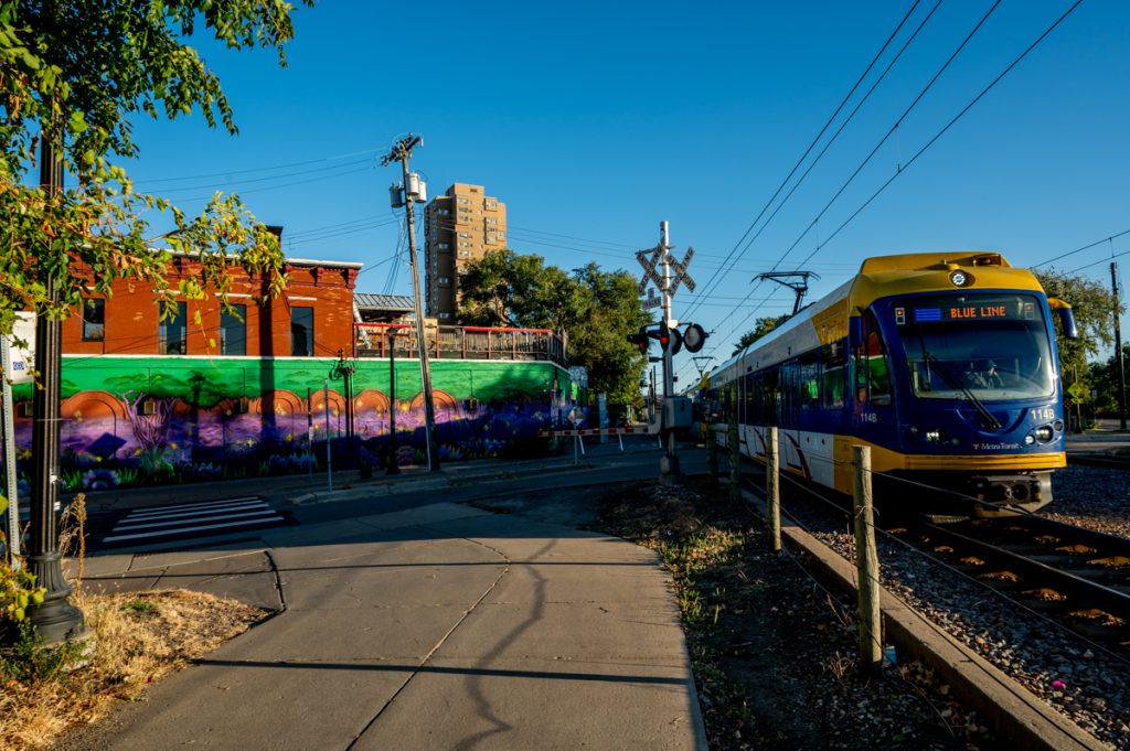 A Blue Line train passing a building with a colorful mural.