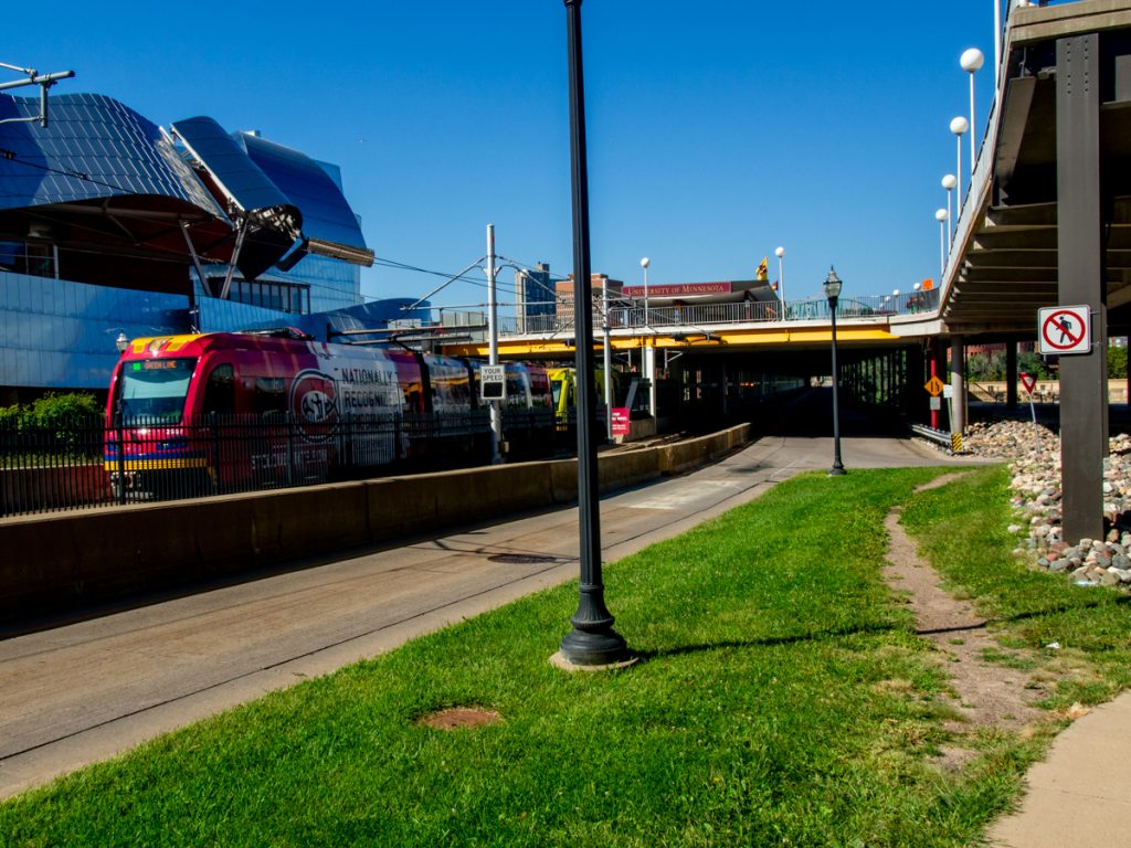 A Green Line train leaving the Washington Avenue Bridge and passing by the Weisman Art Museum.