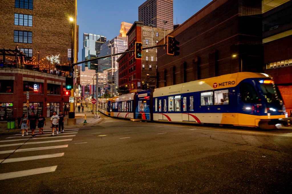 A train in the evening, framed by older brick and newer glass and steel buildings.