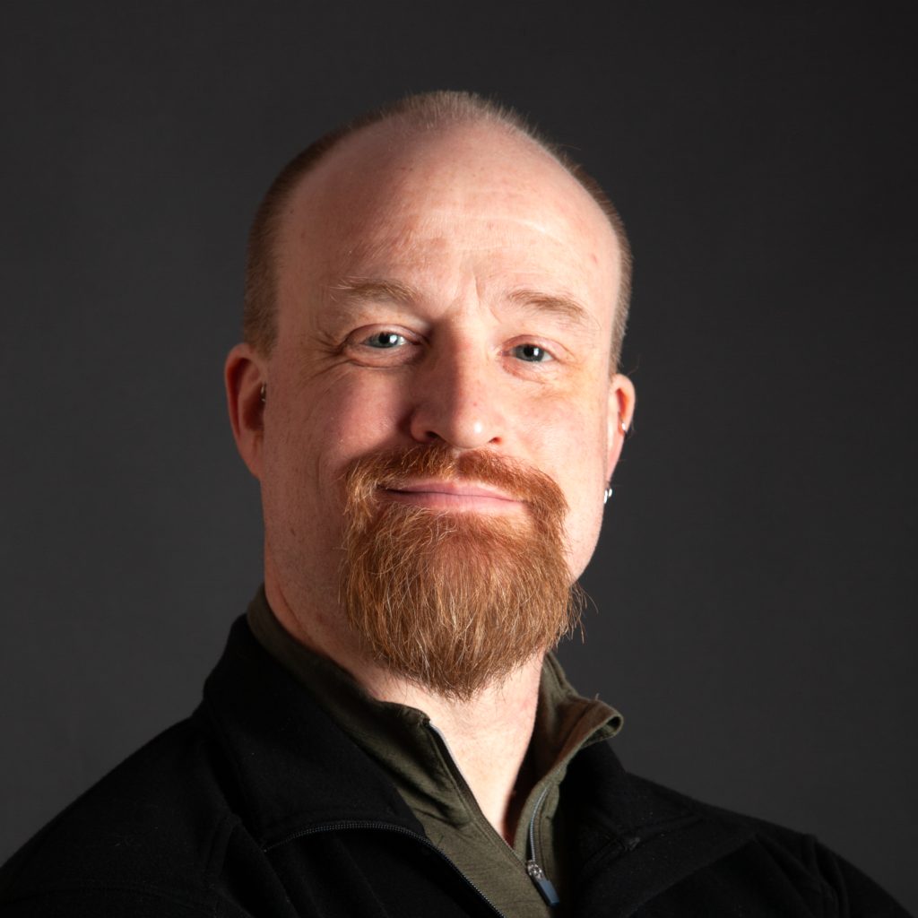 Headshot of a man against a dark backdrop
