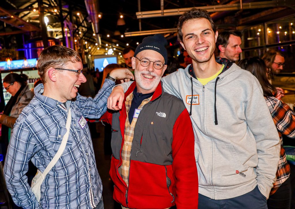 Three men, standing, share a laugh at a celebration for the Bicycle Alliance of Minnesota's 16th anniversary.