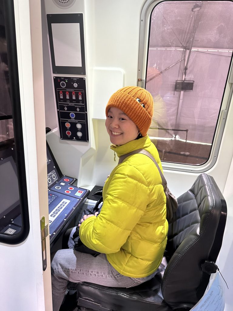 Board member Jane Jackson sits at the driving console for a light-rail train.