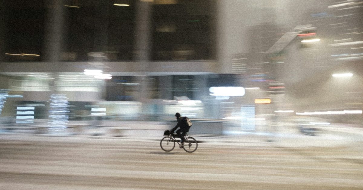 A person riding a bicycle down a Denver street in the snow.