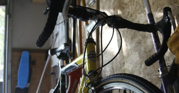 Close-up of a road bike hanging against the wall of a garage.