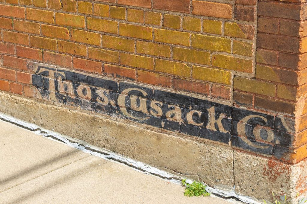 Painted Thomas Cusack sign on the brick building at 171 Front Ave.