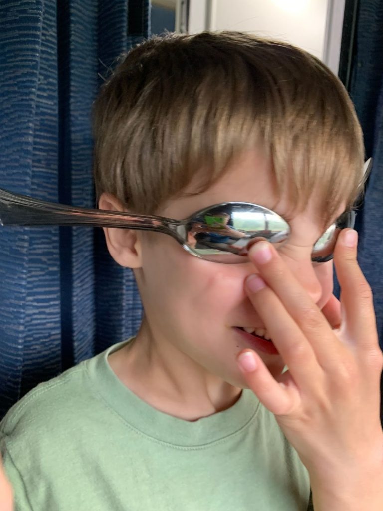 A child holding two spoons over their eyes