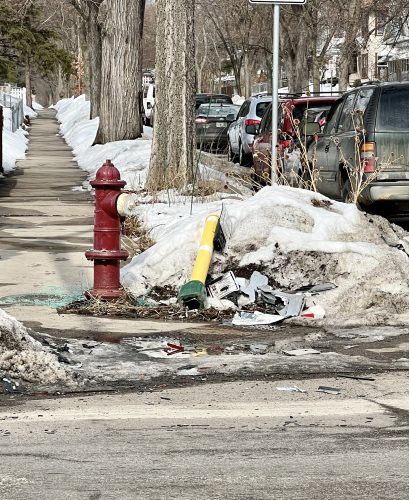 The aftermath of a car crash at a snowy street corner.