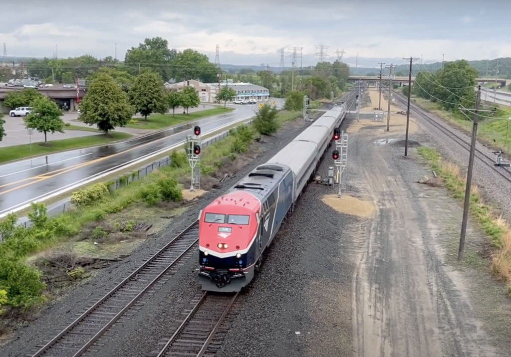 An Amtrak Borealis train travels on wet tracks beneath overcast skies.
