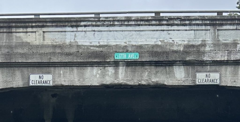 A cropped image of the side of the 17th Avenue bridge with the 17th Ave sign and two No Clearance signs posted on the bridge, spaced to be over where the tracks once stood.