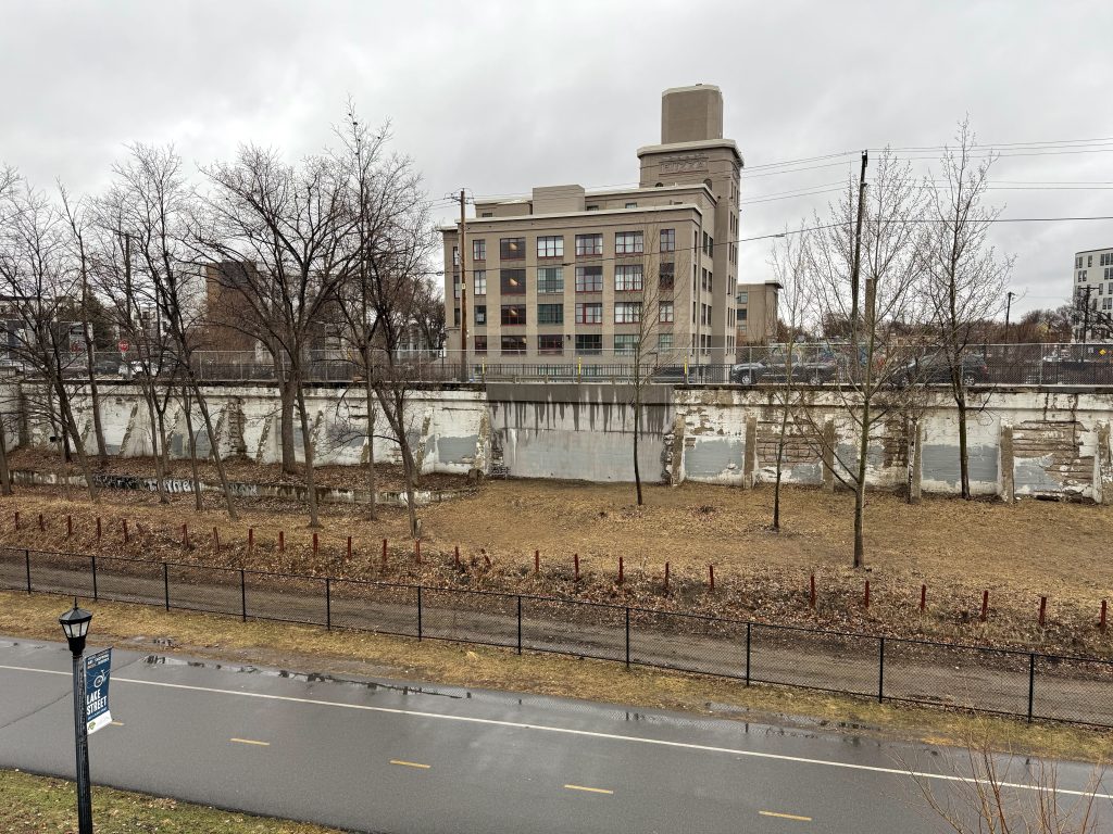Current day view of 29th St W between Colfax and Dupont avenues with the Buzza building behind. The retaining wall has a noticeable modern fill and new concrete in where the bridge used to be.