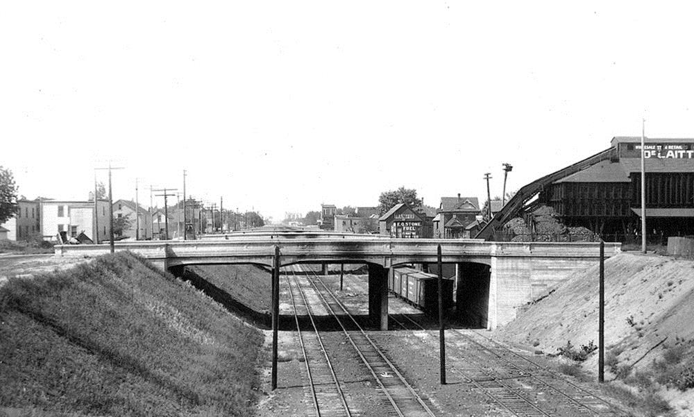 Photo at street level looking down the trench. The 14th Ave bridge is in the foreground with four tracks at this location.
