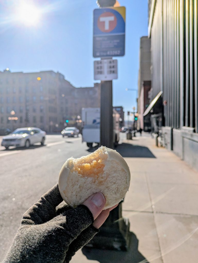 A bao bun held up in front of a bus stop
