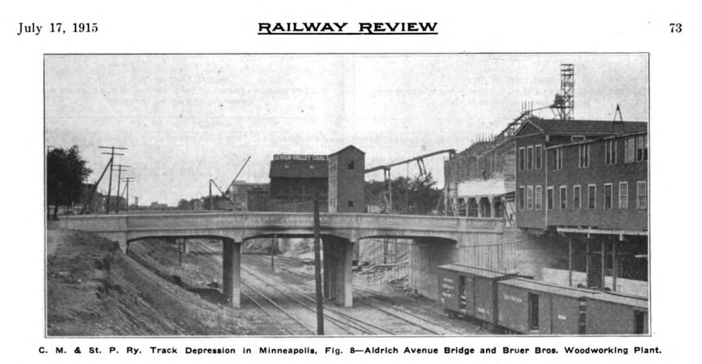 The track depression at Aldrich Ave showing four tracks, box cars, and industry buildings suspended over or near the edge of the trench