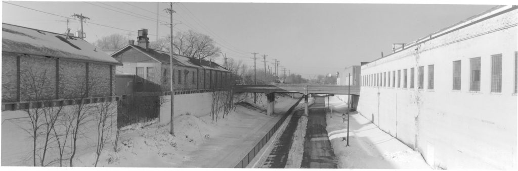 Looking west down the corridor from Pleasant Avenue bridge with industrial buildings on both sides before conversion into housing.