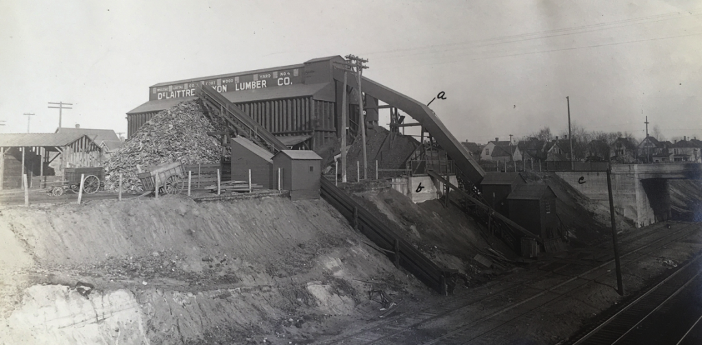 DeLaittre-Dixon Lumber Company with its conveyor and other material transport structures connecting the main building to a side track int he trench.