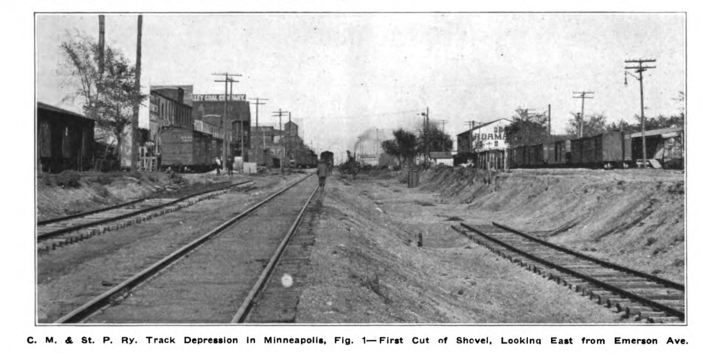 Looking east from Emerson Ave from the at grade 29th St tracks with the first cut and start of the lowering visible. The lowering only appears to be no more than possibly 6ft, and there is partial track laying around.