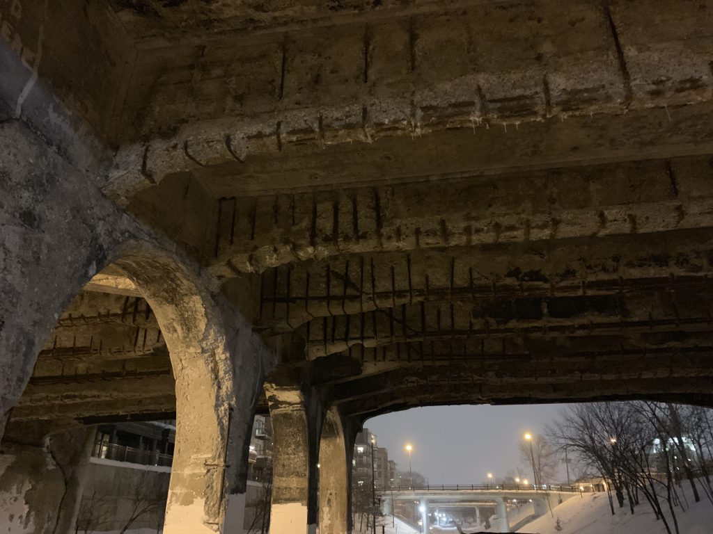 2019 photo of the under side of the old Fremont Avenue S bridge. Rebar is visible on nearly all concrete, which is also flaking and deteriorating.