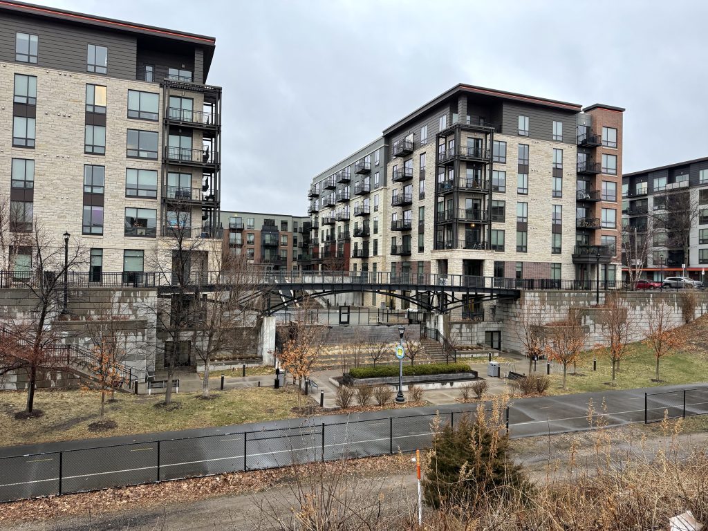 Modern apartment building with a pedestrian bridge crossing what used to be a railroad spur.