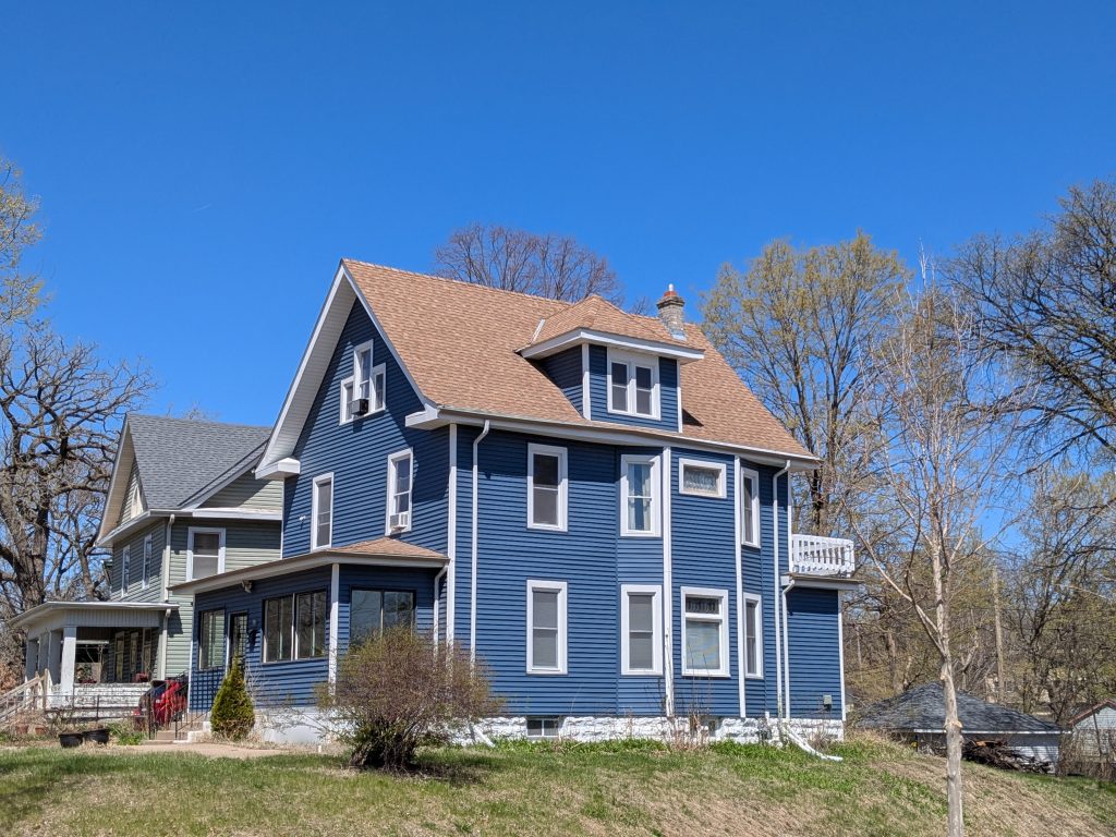 a blue greek-revival house with an enclosed porch