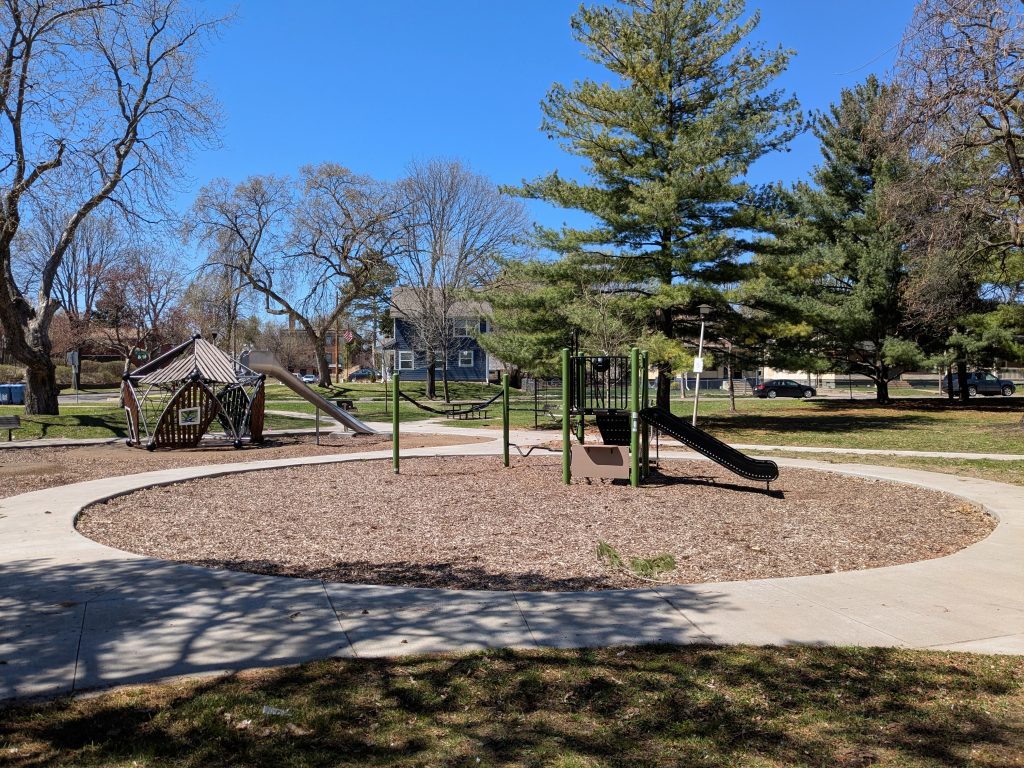 woodchip play area with playground equipment and surrounding concrete paths