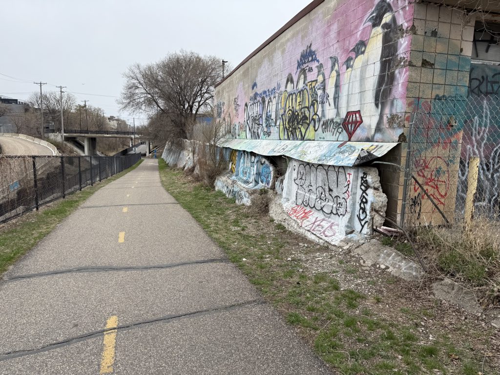 Looking down the access ramp at Nicollet Avenue S with the significantly deteriorated concrete retaining wall to the North.