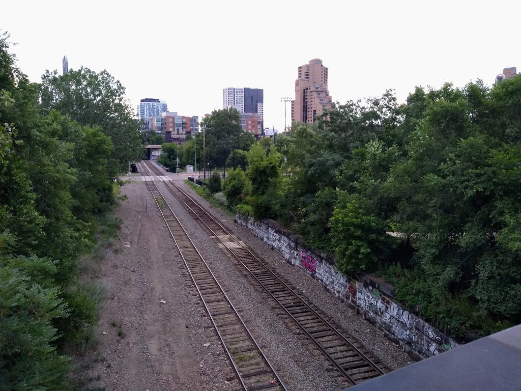 dual railroad tracks with city buildings in the background