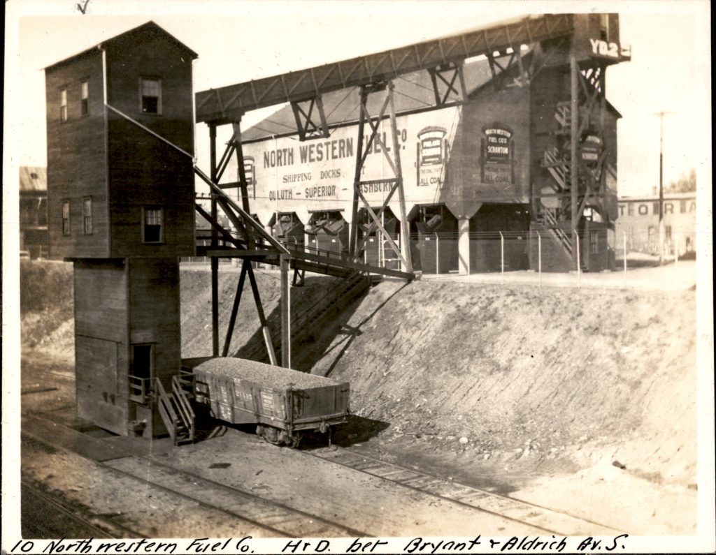 North Western Fuel Company showing a large building at grade, and a complex conveyor structure and tower into the trench to allow access to a side track.
