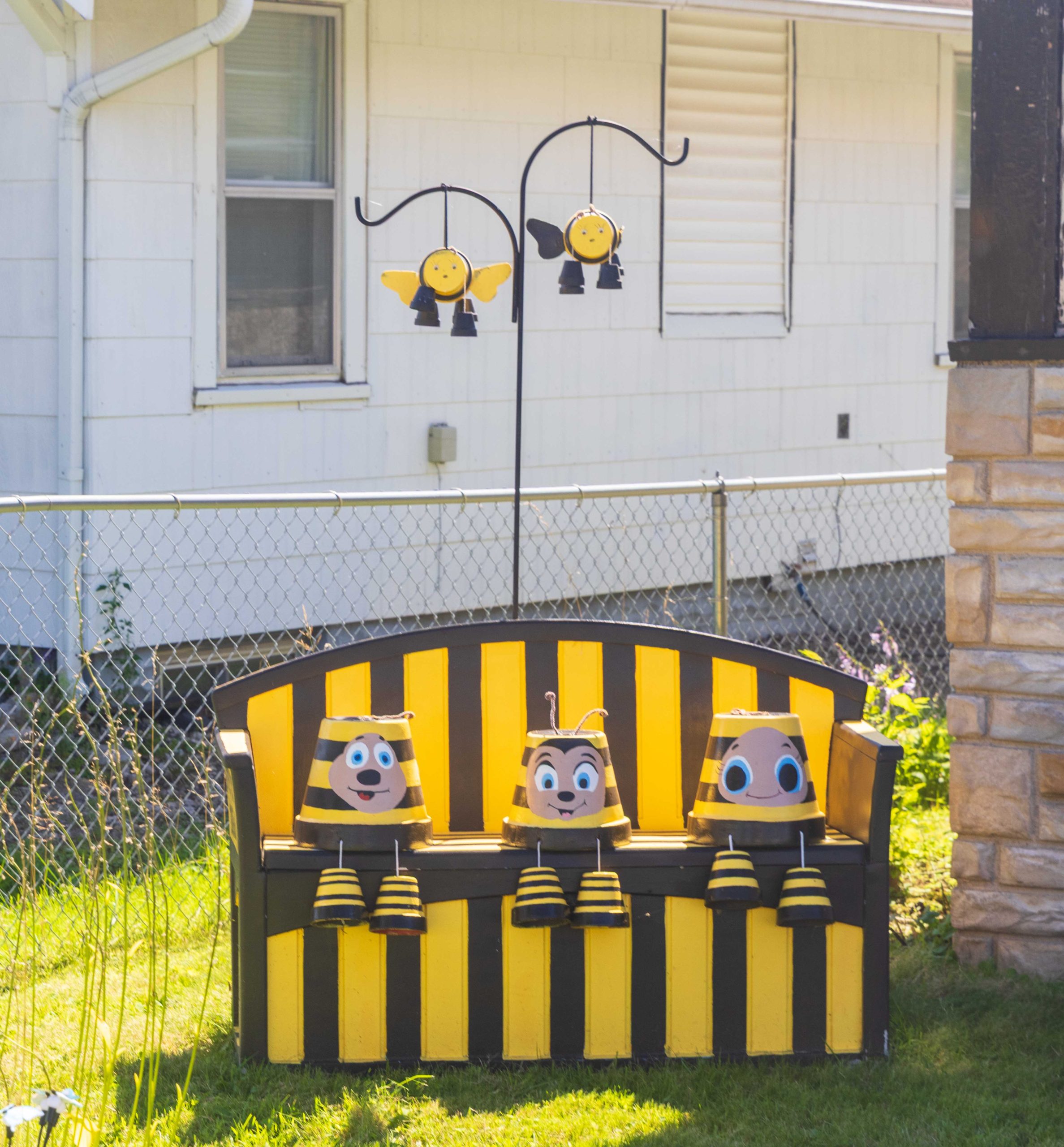 Yellow and brown bee bench with clay pots decorated like bees.