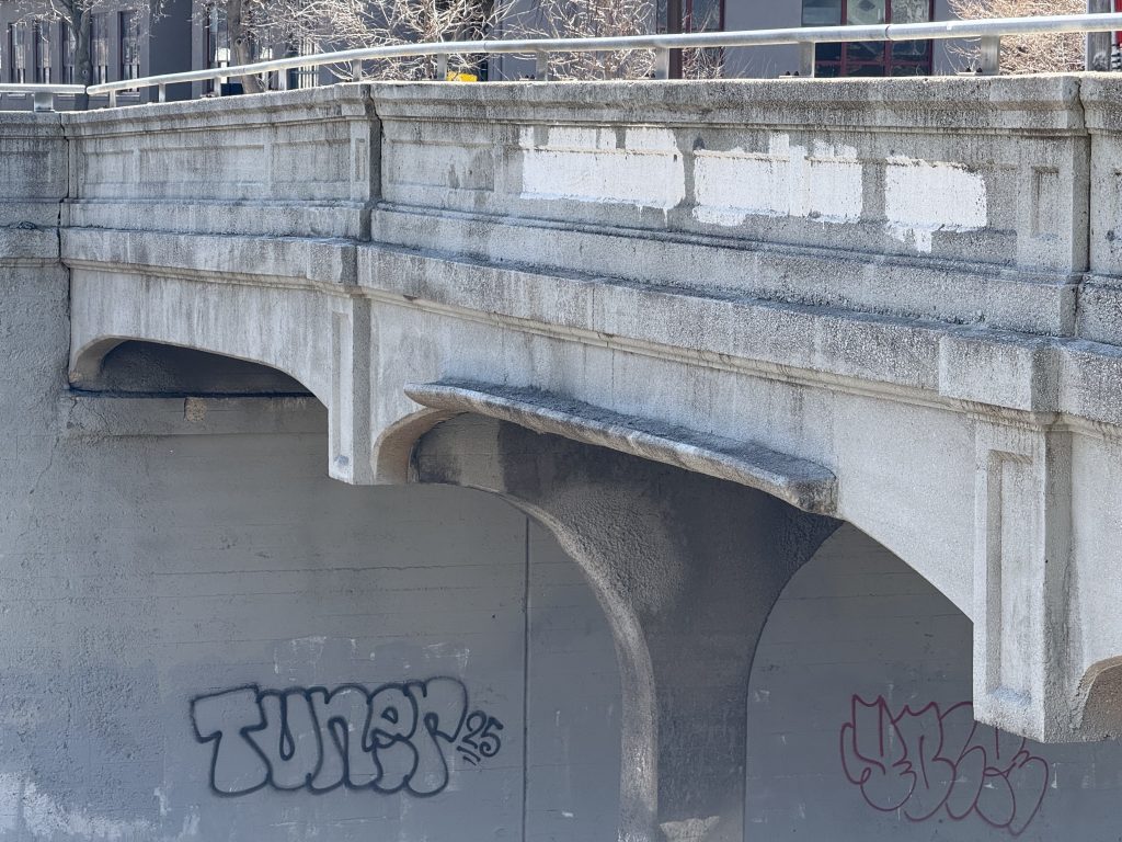 Colfax Ave bridge with a smoke shield made of concrete attached to the bridge over the center span of the main tracks.