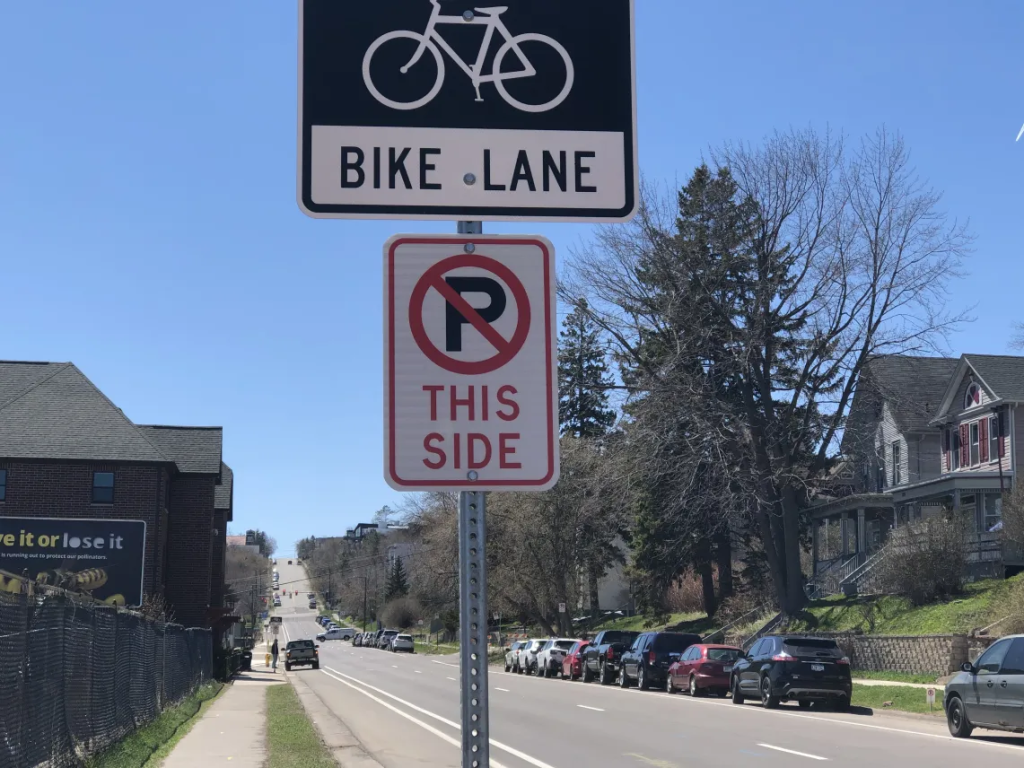 A "No Parking" sign next to a bike lane on a tree-lined street in Duluth, Minnesota.