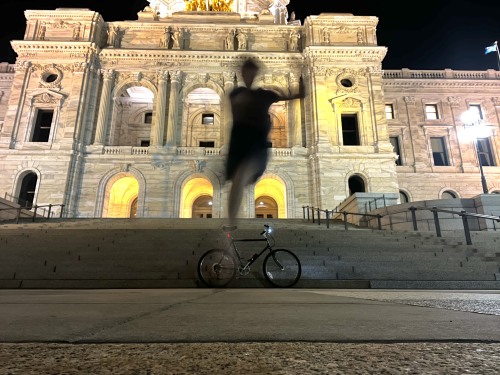 Dancing in front of the Minnesota State Capitol, with a bike resting along the steps.