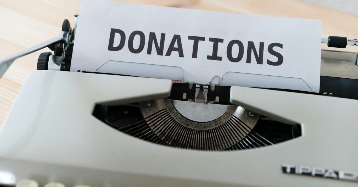 A manual typewriter has a sheet of paper in the role that reads DONATIONS.